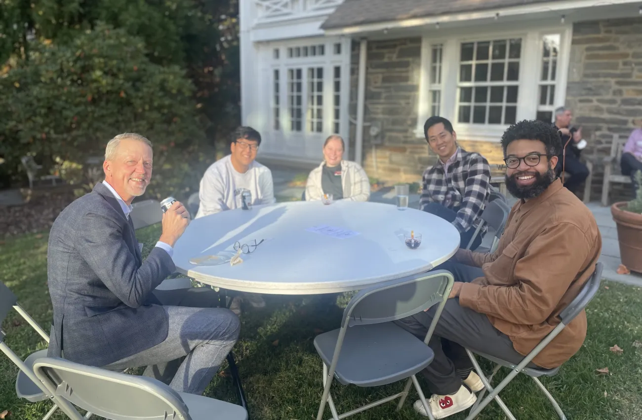 faculty and staff sit at circle table outside