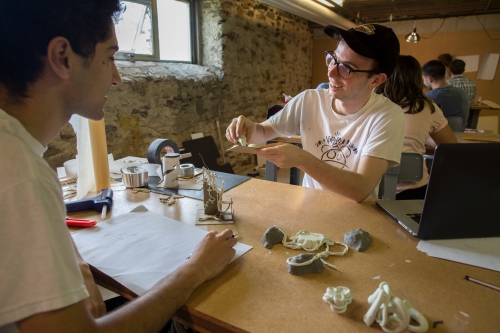 two young men at a work table creating models
