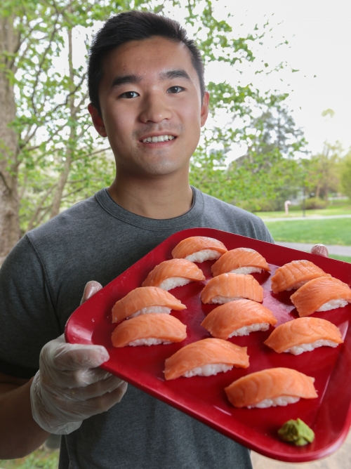 Henry Han ’20 holding a red plate of sushi he made