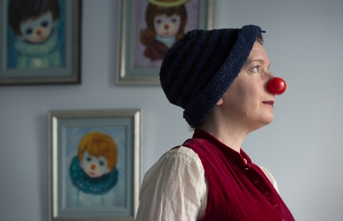 woman in a clown nose standing in front of a wall with paintings