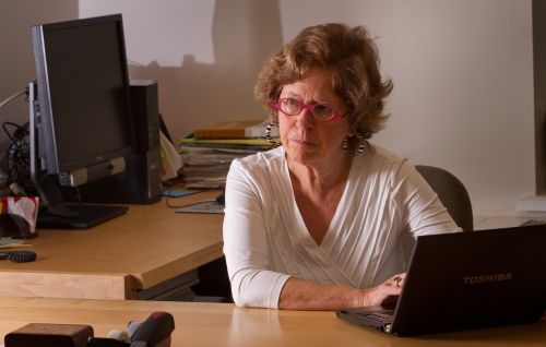 professor in white blouse and magenta glasses