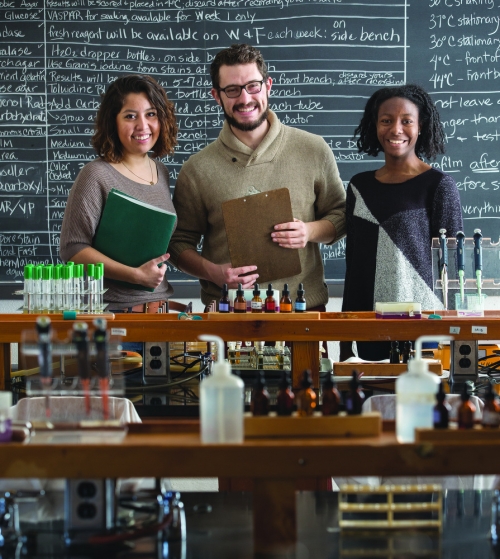 three students stand in front of a classroom