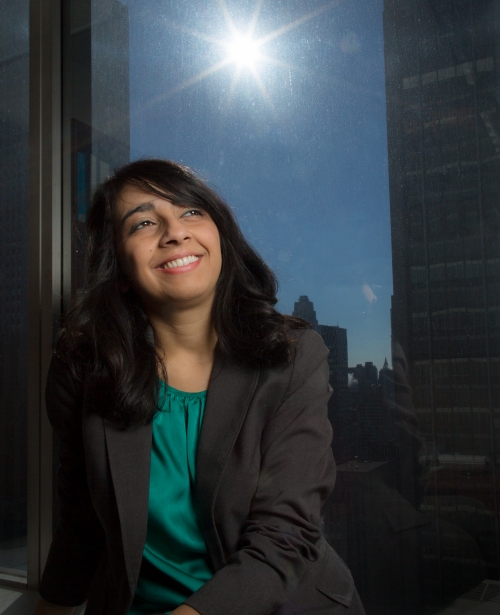 Urooj Khan ’10 in a suit, looking up as the sun shines behind her.