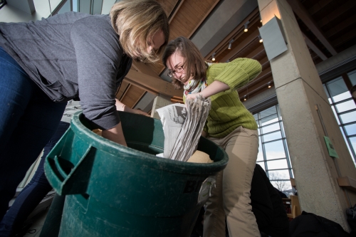 Aurora Winslade and Melissa Tier ’14 reaching into a recycling bin