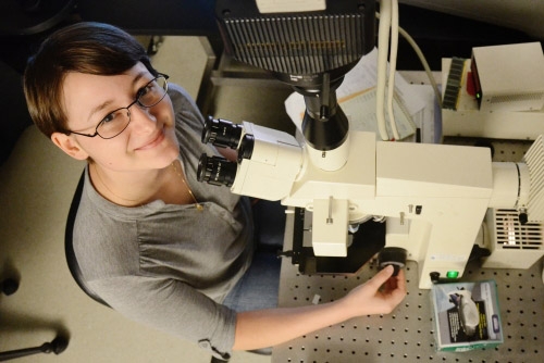 Rebecca Senft at a microscope looking up