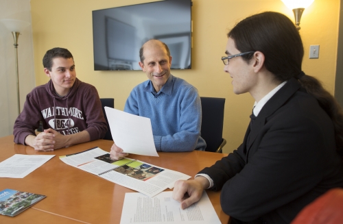 Three men around a computer 