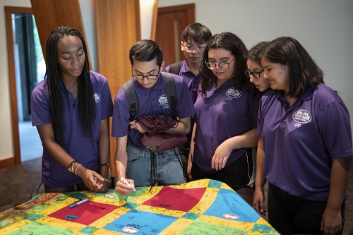 S3P students dressed in purple shirts signing a poster