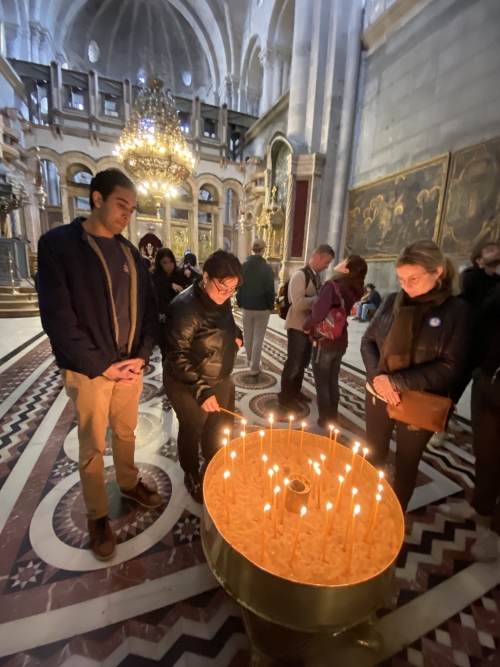 A student lighting a candle in a church