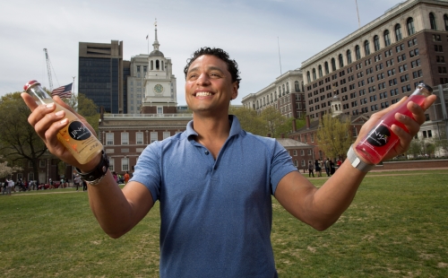 A man smiles holding bottles of food 