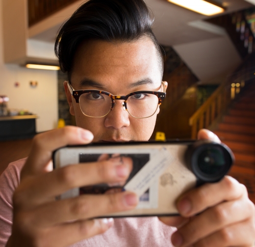 A man with glasses looks at a camera