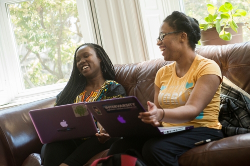 Two female students with computers on a couch