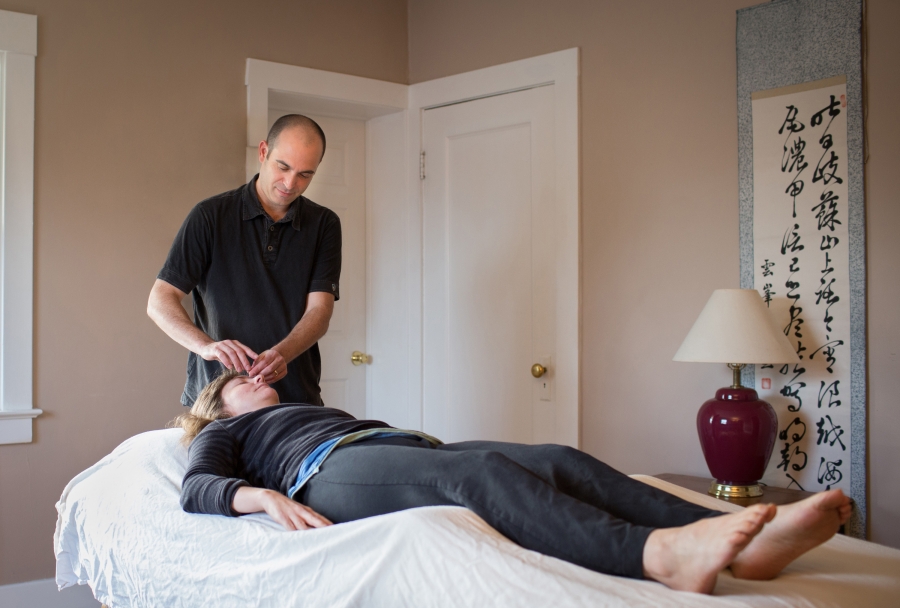 male practitioner performs acupuncture on female patient