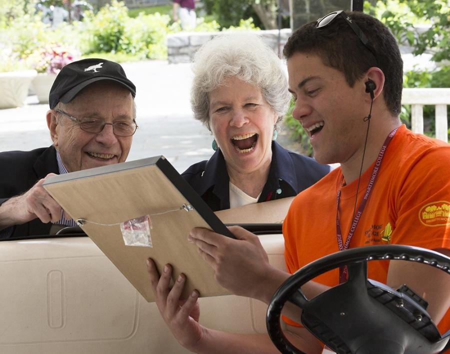 three attendees smile and chat in a golf cart