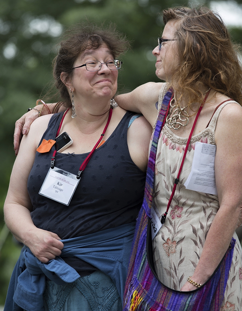 An alumna puts her arm around another's shoulder as they walk and talk