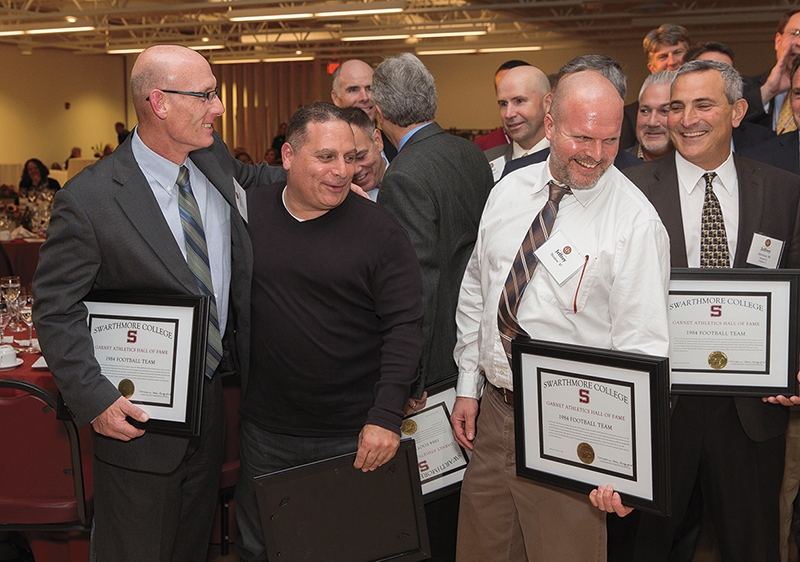 A group of middle-aged men hold plaques and smile.