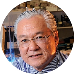 Joseph Takahashi ’74—Public Health Adviser is an older man with glasses and white hair looking at the camera. 