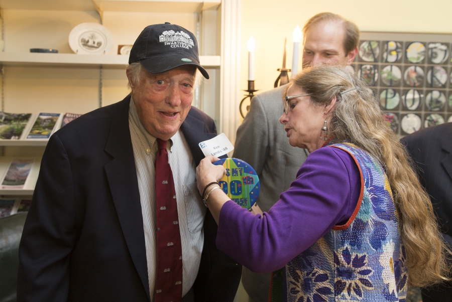 A woman pins a name tag on the jacket of a man. 