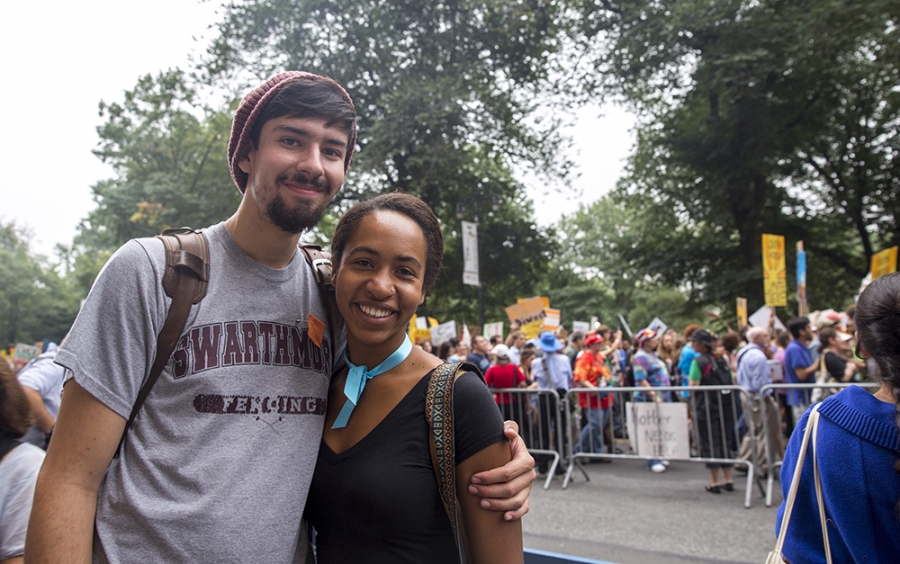 A young man and woman smiled and have their arms around each other. 