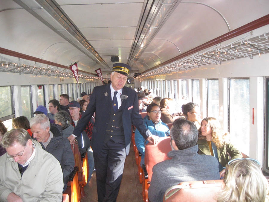 A conductor walks down the aisle of a full train. Conductor is Frank Moscatelli as a guide. Photos by Jim Moskowitz ’88.