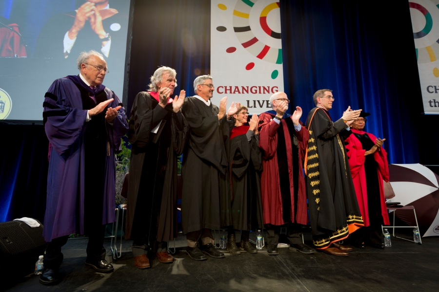 Robed administrators clap on stage for Val Smith