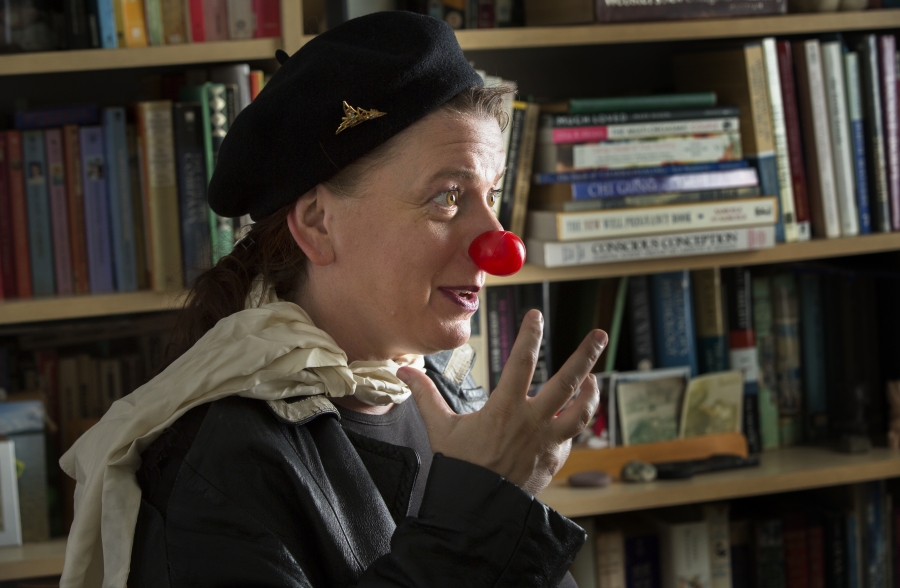 Kendall Cornell talks passionately in front of a bookcase while wearing a clown nose
