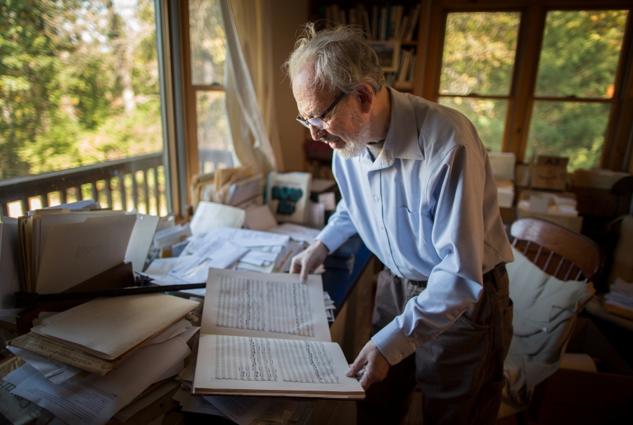 A man is standing in a room looking at a book. 