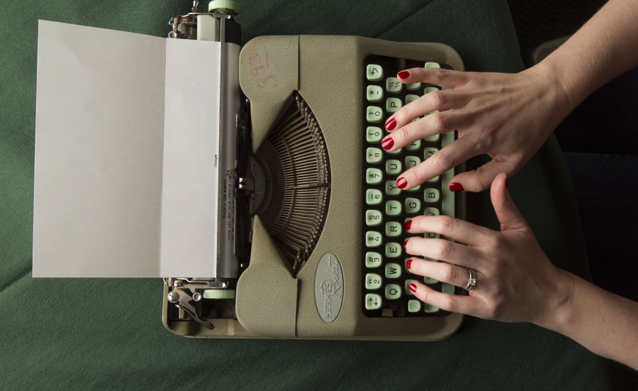 Hands typing on a green typewriter