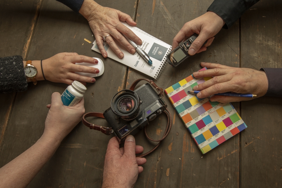 six hands holding office objects