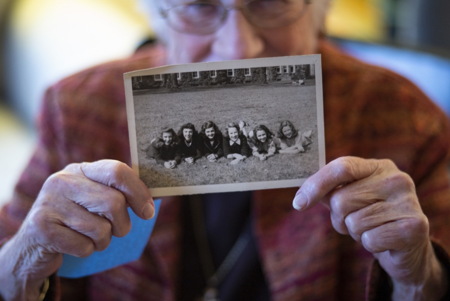 Barbara Lea Couphos holding a B&W photo of six women