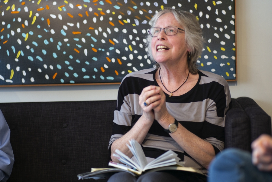 Woman clasps hands and smiles 