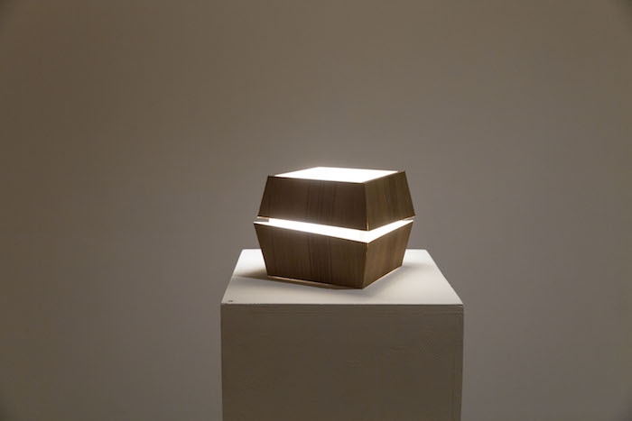 A cube-like wooden lighted lamp structure.