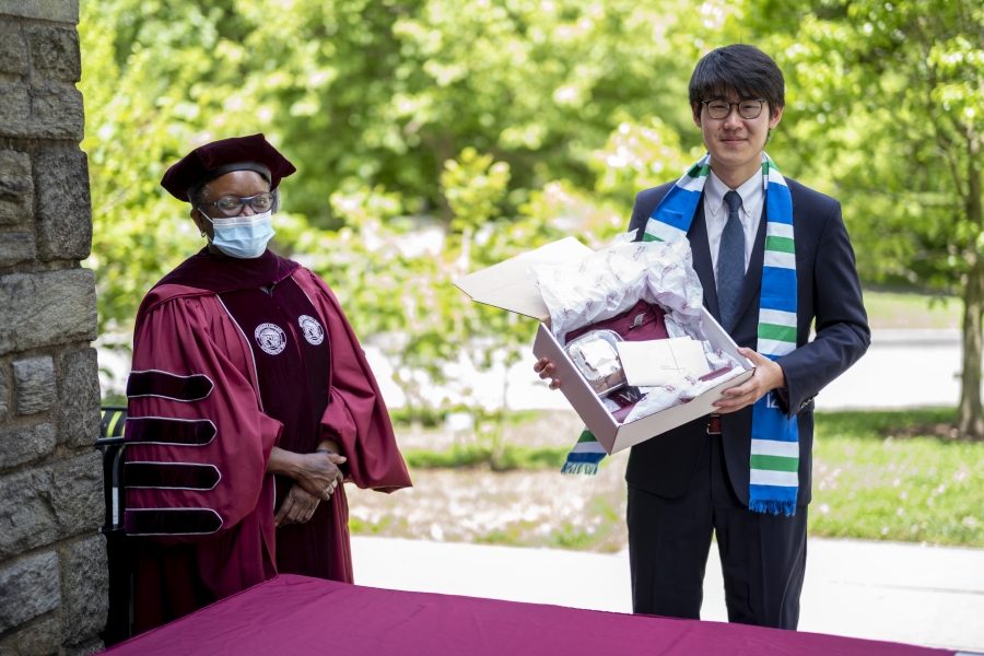 Portrait of President Valerie Smith in regalia with graduation gift for student