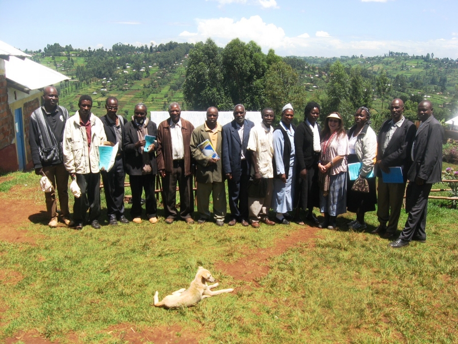 A group of people posing in a line, with a green hill in the background