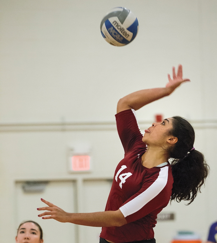 A woman hits a volleyball into the air.