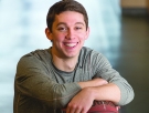 young man leans on a basketball sitting on a recycling bin