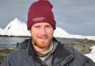 Wiley Archibald ’10 holds a days-old Antarctic fur seal pup with a still-attached umbilical cord.