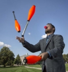 John Rieffel juggling in a suit and clown nose