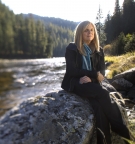 portrait of Anna Peterson ’83 sitting on a rock by a river