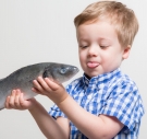 A boy sticking his tongue out at a fish