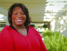 Sabrina Martinez ’92 smiles in front of ferns