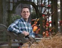 Josh Coceano sitting in a beautiful nature setting with autumn leaves