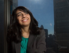 Urooj Khan ’10 in a suit, looking up as the sun shines behind her.