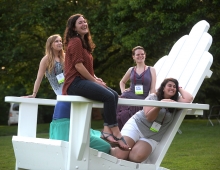 alumni sit on a big adirondack chair smiling