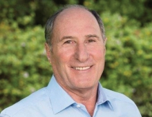 John Goldman is a bald man with a nice smile looking at the camera.