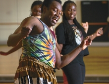 An African American man is dancing in a room with students. 