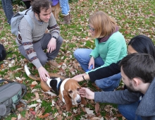 Students crouch around a basset hound while petting him.