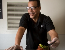 A man stands behind a tray of food. 