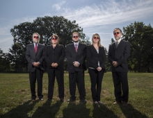 Bulletin staffers standing on Parrish Beach wearing dark suits, sunglasses, and clown noses
