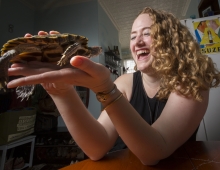 woman holds turtle both appear content