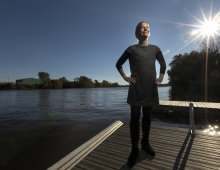 woman stands on dock near river 